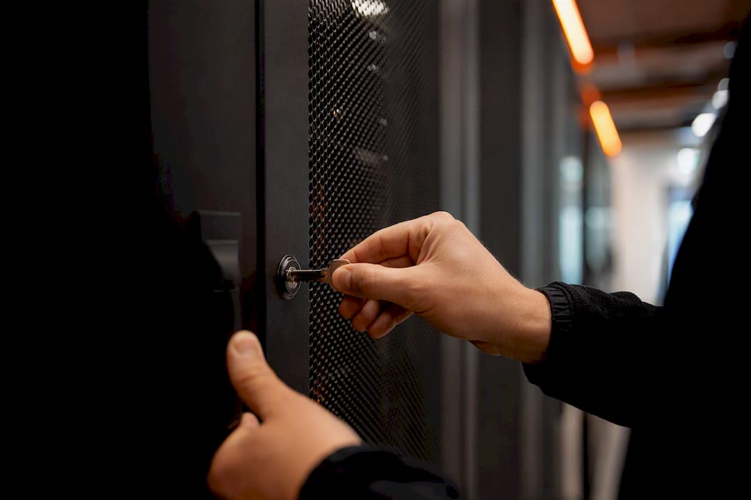 Hands turning physical key in server lock