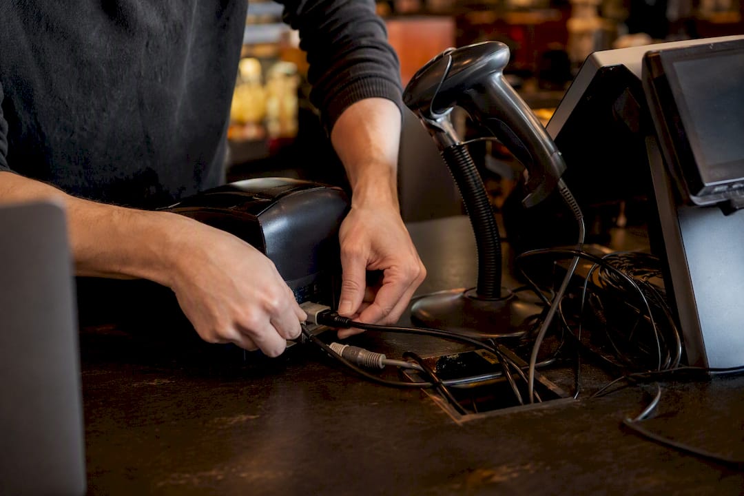 Hands plugging hardware cables at POS station