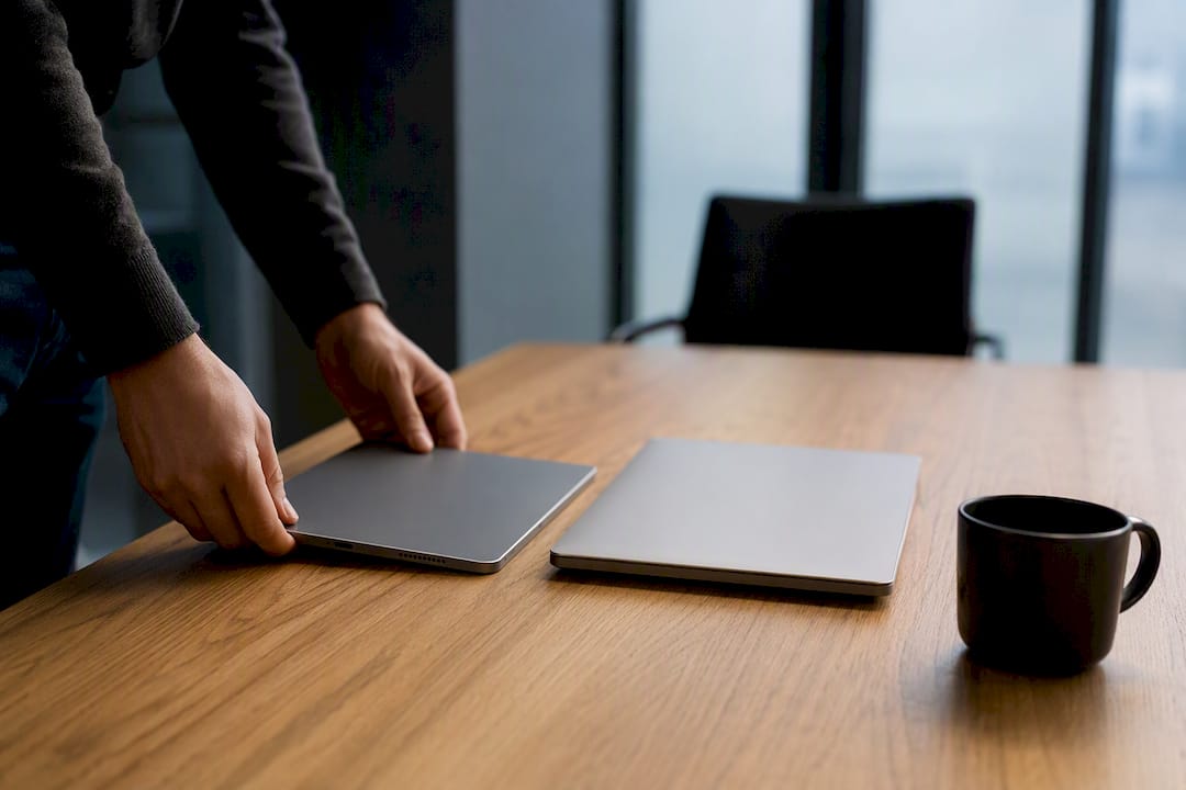 Hands placing smartphone next to laptop on desk